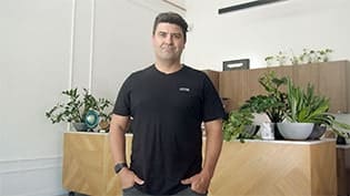 Fresho Software for fresh food wholesale suppliers and their customers - Managing Director of Common Roasters standing in front of a coffee bar with plants