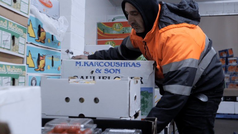 A picker picking up boxes of fruit in a warehouse