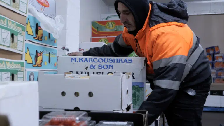 A picker picking up boxes of fruit in a warehouse